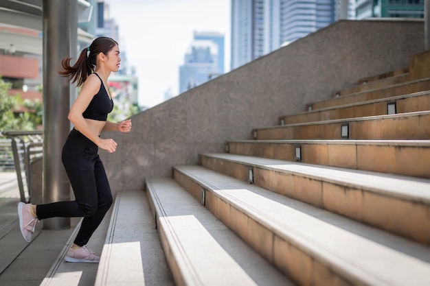 Foto una mujer del sudeste asiático con ropa de gimnasia subiendo escaleras al aire libre.