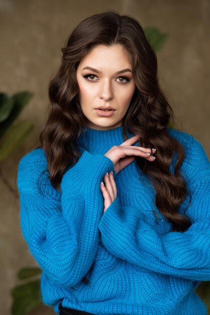 Una mujer con un suéter azul con cabello castaño largo y un suéter azul.