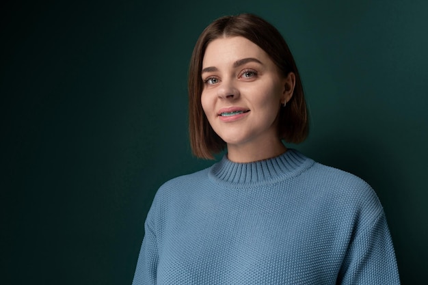 Mujer con suéter azul contra la pared verde