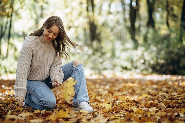 Mujer en suéter cálido caminando en el parque de otoño