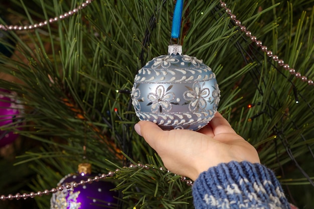 Mujer con suéter decorando el árbol de Navidad con pelotas de juguete