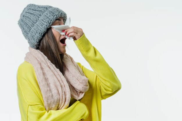 Mujer en un suéter, gorro de punto, bufanda estornuda