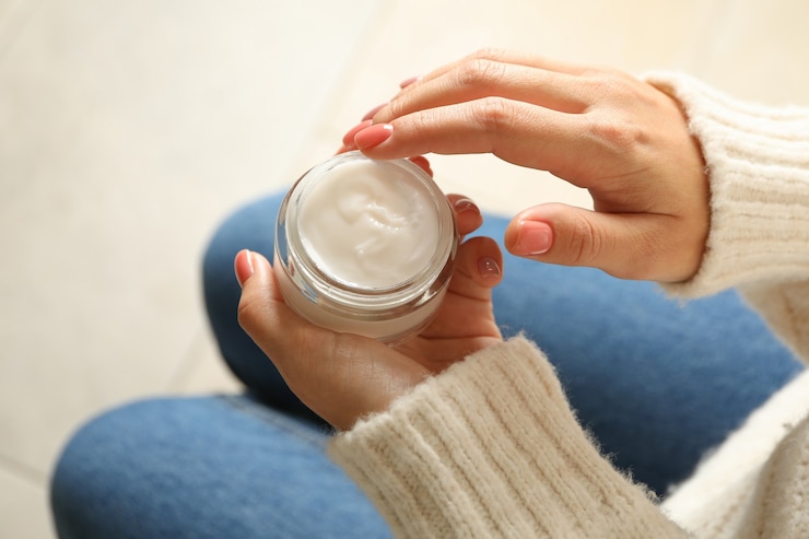 Foto mujer en suéter y jeans mantenga tarro de crema cosmética