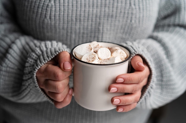 Mujer con suéter de punto con sabroso cacao con malvavisco en taza