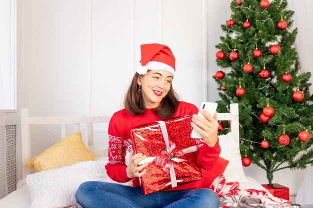 Mujer con un suéter rojo cerca del árbol de Navidad