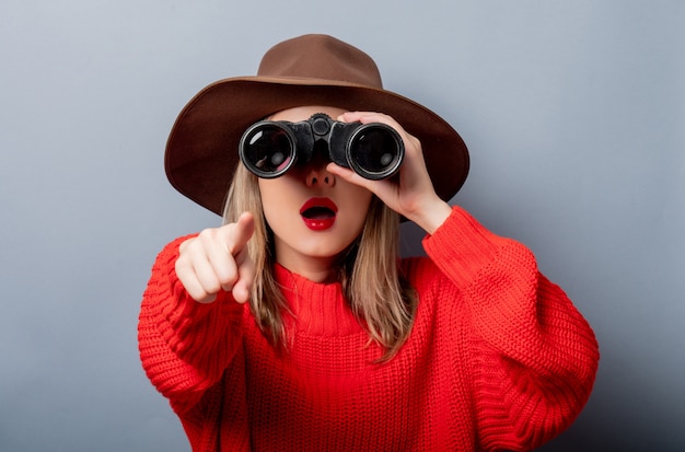 Mujer con suéter rojo y sombrero con binoculares