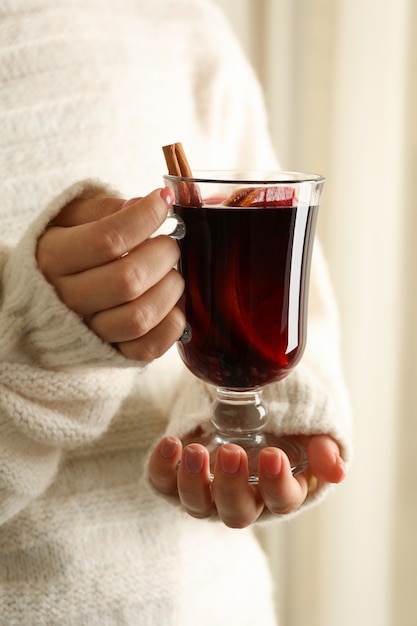 Mujer en suéter sostenga una copa de vino caliente