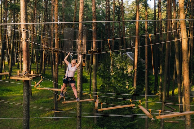 Una mujer supera un obstáculo en un pueblo de cuerdas Una mujer en un parque de cuerdas del bosque