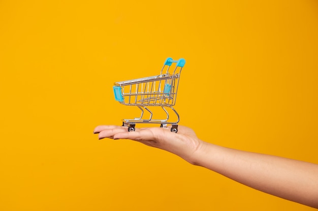 Mujer y el supermercado, ella muestra un mini carrito. Concepto de compras de promoción.