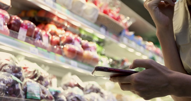 Mujer en el supermercado usando Smartphone Closeup