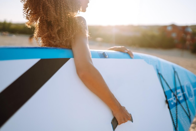 Mujer surfista camina con una tabla en la playa de arena Deporte extremo Estilo de vida de fin de semana de viaje