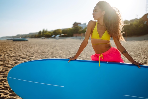 Mujer surfista camina con una tabla en la playa de arena Deporte extremo Estilo de vida de fin de semana de viaje