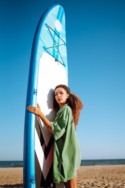 Foto mujer surfista camina con una tabla en la playa de arena deporte extremo estilo de vida de fin de semana de viaje