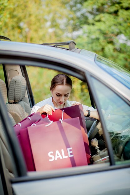 Mujer con sus bolsas de compras en el coche - concepto de compras.