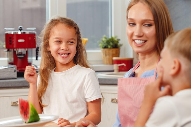 Mujer y sus hijos cocinando en la cocina