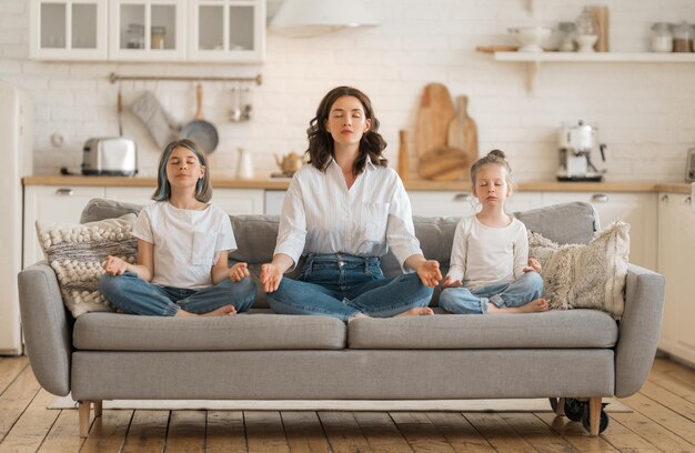 La mujer y sus hijos están meditando en casa.