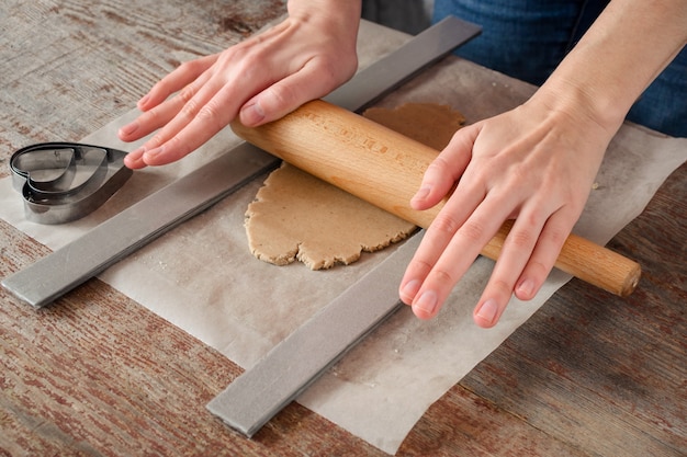 Mujer con sus manos rollos de pastelería para una galleta con un rodillo