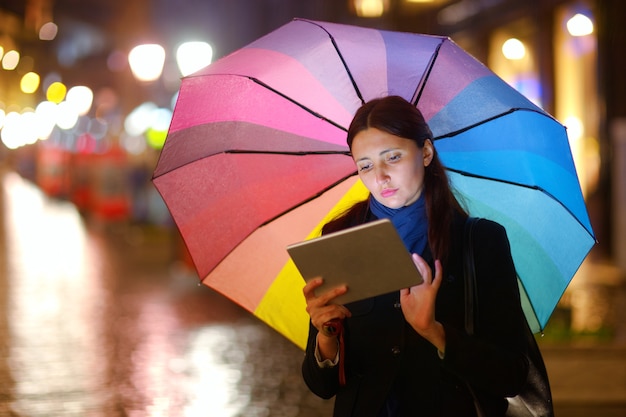 Mujer con Tablet PC bajo la lluvia