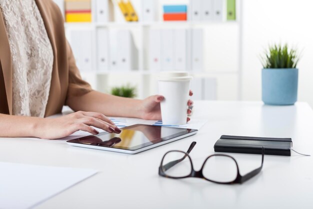 Mujer con tableta y café en la oficina