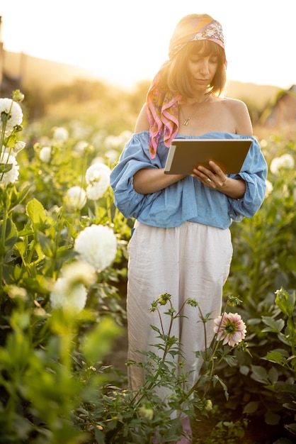 Mujer con una tableta digital en la granja de flores al aire libre