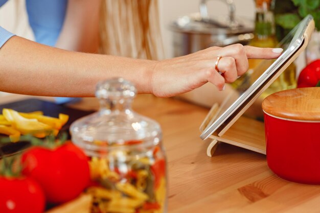 Mujer con tableta digital mientras cocina en la cocina