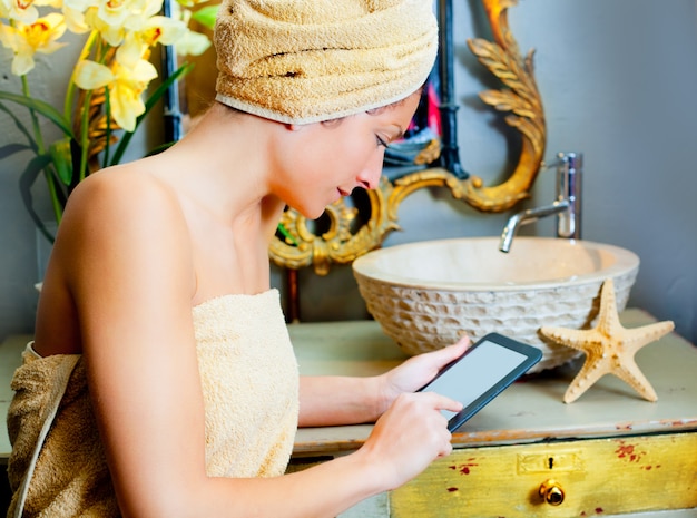 Mujer en la tableta del ebook del baño que lee