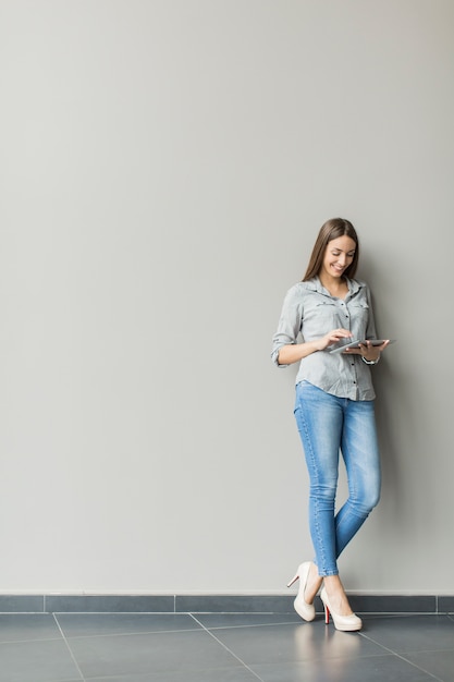 Mujer con tableta junto a la pared