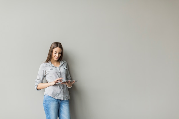 Mujer con tableta junto a la pared