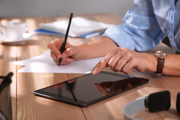 Mujer con tableta moderna aprendiendo en la mesa en el interior de primer plano