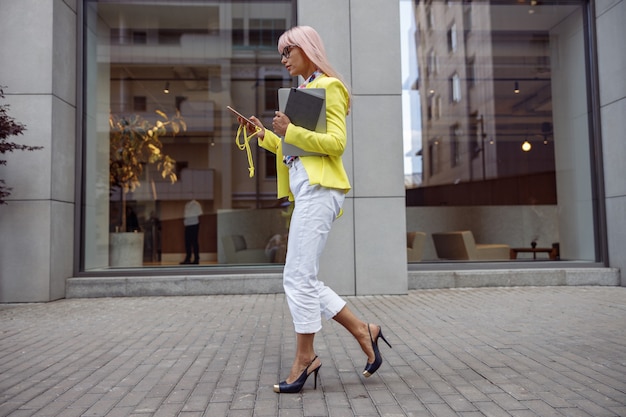 Mujer en tacones mirando a la pantalla del teléfono móvil mientras camina