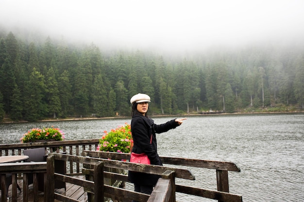 Mujer tailandesa asiática viaja y camina en el puente de madera frente al mar en el lago Mummelsee mientras llueve en el Bosque Negro o Schwarzwald en Badenwurttemberg de Stuttgart Alemania