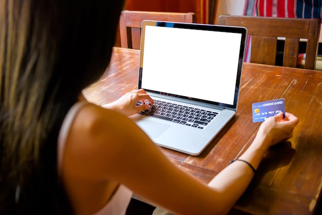 Mujer tailandesa bebiendo jugo de naranja en un café Usando laptop comprando en línea Trabajar con una computadora en una cafetería