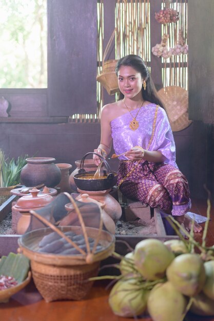 Mujer tailandesa cocinando en vestido tailandés retro