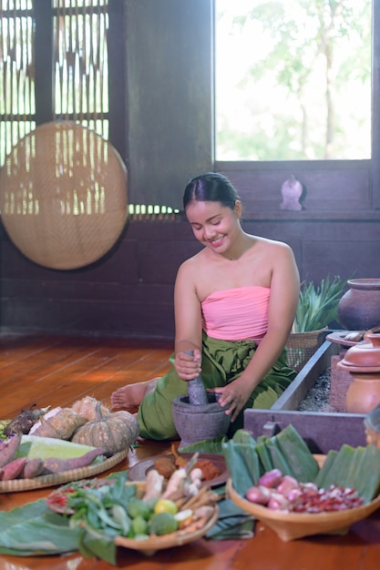 Mujer tailandesa cocinando en vestido tailandés retro