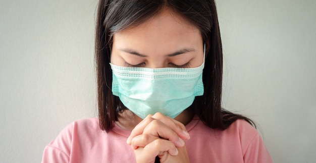 Foto mujer tailandesa que usa una máscara para proteger el virus, covid 19 orando por las bendiciones de dios para que el mundo esté a salvo de esta epidemia.