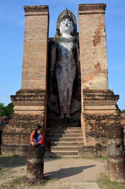 Mujer tailandesa viaja y retrata con la antigua gran estatua de Buda y el edificio antiguo en la ciudad histórica de Sukhothai y las ciudades históricas asociadas en Sukhothai Tailandia