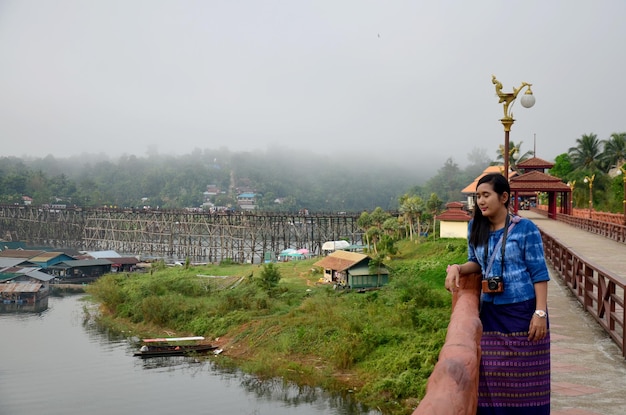 Mujer tailandesa viaje y retrato en el puente de madera Saphan Mon en la mañana en Sangkhlaburi el 4 de diciembre de 2015 en Kanchanaburi Tailandia