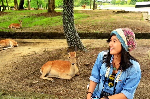 Mujer tailandesa viajera sentada y posa para tomar una foto con ciervos en el Templo Todaiji de la región de Kansai el 9 de julio de 2015 en Nara Japón