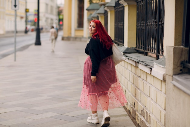 Mujer de talla grande europea joven cuerpo de pelo rosa roja chica positiva caminar en las calles de la ciudad al aire libre