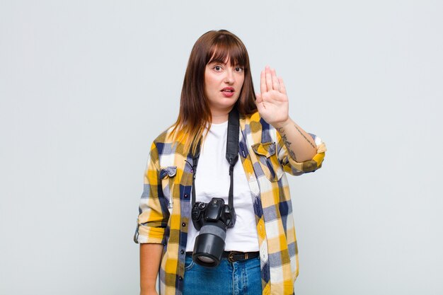 Mujer de talla grande que parece seria, severa, disgustada y enojada mostrando la palma abierta haciendo gesto de parada