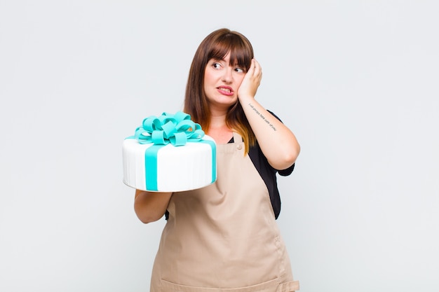 Mujer de talla grande que se siente aburrida, frustrada y con sueño después de una tarea aburrida, aburrida y tediosa, sosteniendo la cara con la mano