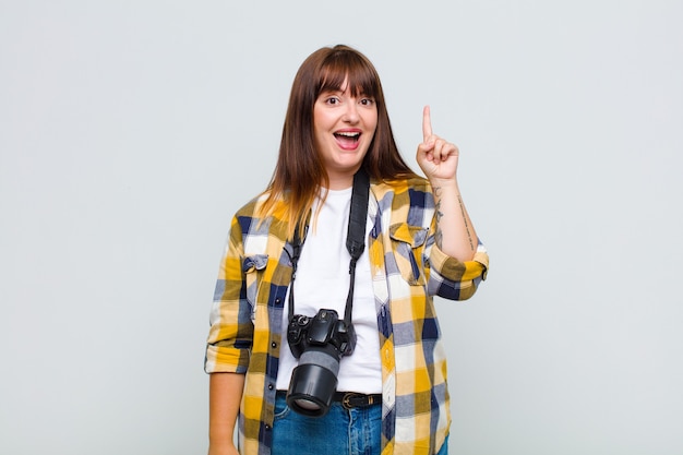 Foto mujer de talla grande que se siente como un genio feliz y emocionado después de realizar una idea, levantando alegremente el dedo, ¡eureka!