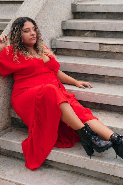 Una mujer de talla grande, sentada en el parque disfrutando de la vida. Una mujer joven con sobrepeso con un vestido elegante. Belleza natural