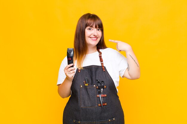 Mujer de talla grande sonriendo con confianza apuntando a su propia sonrisa amplia, actitud positiva, relajada y satisfecha