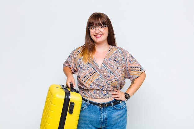 Mujer de talla grande sonriendo felizmente con una mano en la cadera y una actitud segura, positiva, orgullosa y amistosa