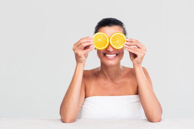 Mujer tapándose los ojos con rodajas de naranja