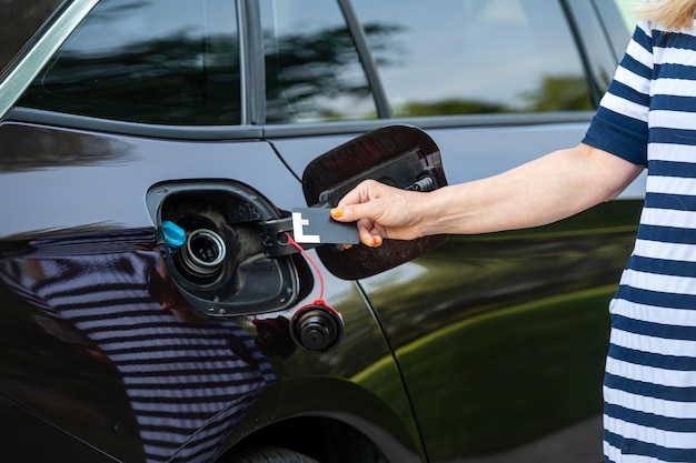 Mujer con tarjeta de crédito frente al concepto de aumento de precio de combustible de tanque de gas abierto manos primer plano