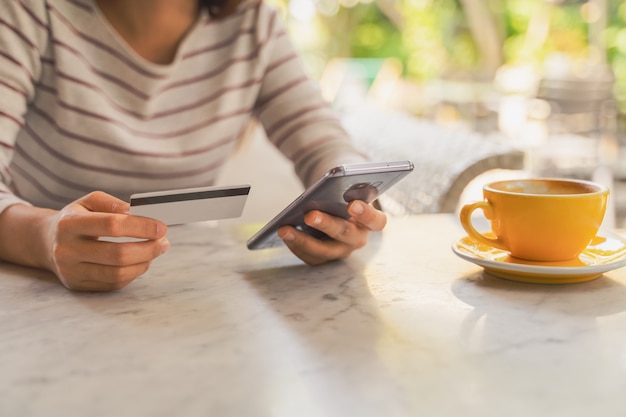 Mujer con tarjeta de crédito o débito por aplicación en el teléfono inteligente para el pago en línea