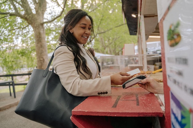 Mujer con tarjeta de crédito pidiendo comida, haciendo el pago con terminal electrónica