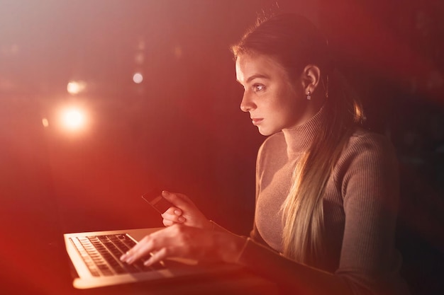 Mujer con tarjeta de crédito en sus manos mirando en la computadora portátil onl